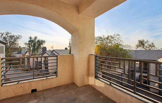 A balcony with a metal railing and a concrete floor.