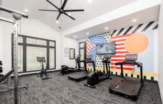 a fitness room with treadmills and weights and a large window