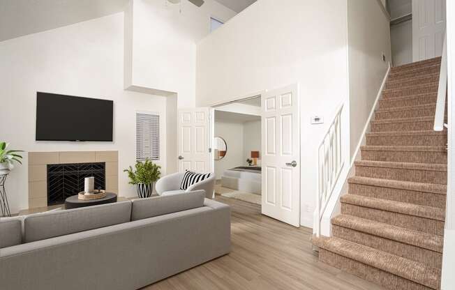 a living room with a staircase and a tv above a fireplace