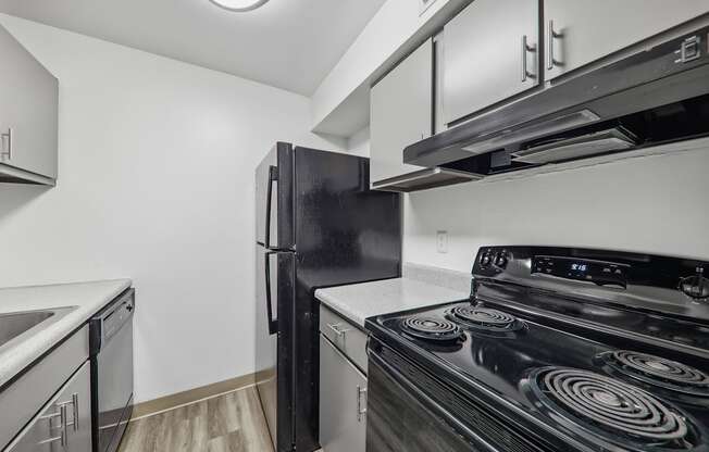 a kitchen with white cabinets and black appliances and a refrigerator at The Avalon Apartment Homes, Missouri