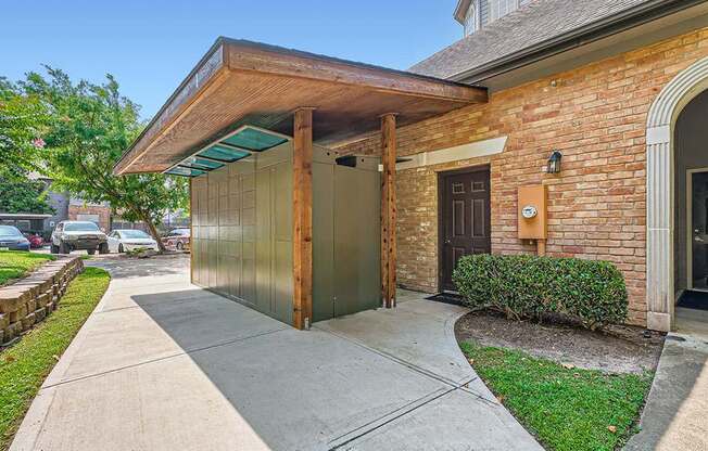 A brick house with a wooden porch and a green bush.