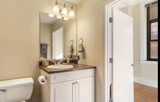 A bathroom with a white toilet and a white sink with a brown counter.