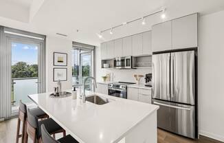 a white kitchen with a large island and stainless steel appliances