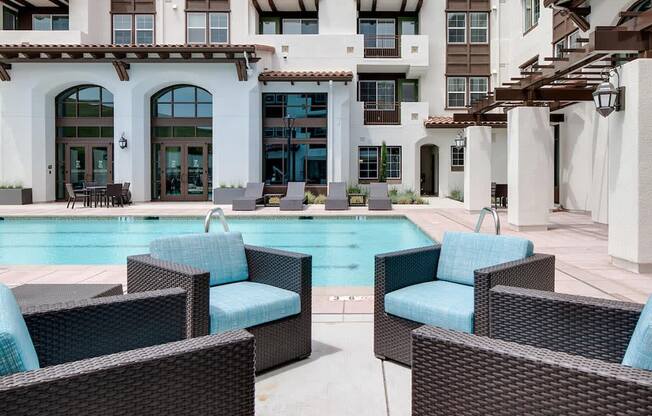 a swimming pool with blue chairs in front of a building