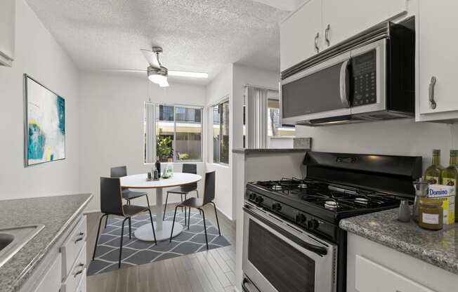 a kitchen and dining room with a stove and microwave and a table and chairs at Pacific Rose, Los Angeles, CA