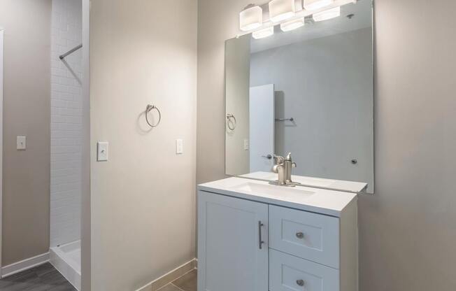 A white bathroom vanity with a mirror and lights above it.