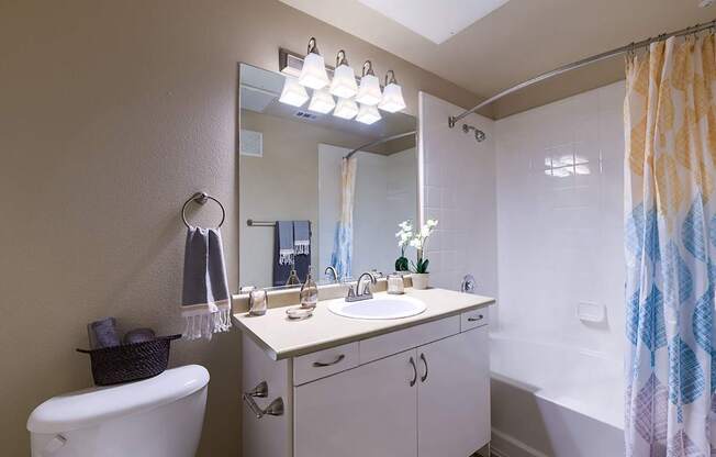 A bathroom with a white tub, sink, and shower curtain.