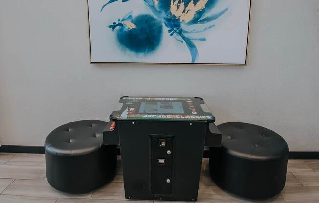 Clubhouse game table and two large black ottomons.