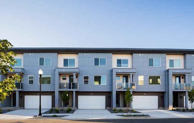 A row of modern townhouses with garages and driveways.