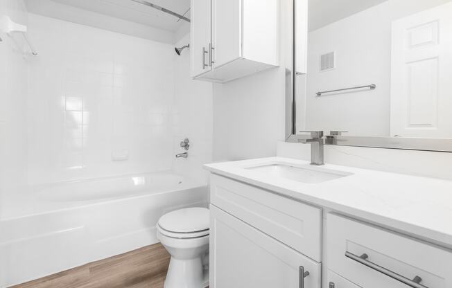 a bathroom with white cabinetry and a white bathtub