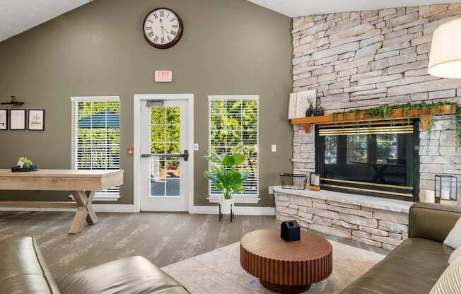 A clubhouse room with a stone fireplace and a large clock on the wall at Clackamas Trails Apartments, Oregon, 97222