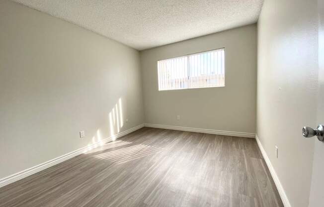 an empty living room with wood floors and a window