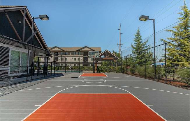 A basketball court with a red surface and white lines at Forestplace Apartment Homes, Forest Grove