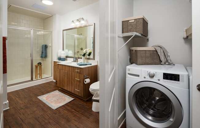 a bathroom with a washing machine and a toilet and a shower