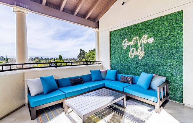 a patio with blue couches and a table and a green wall