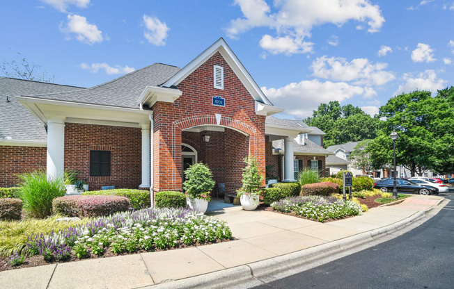 the front of a brick house with a sidewalk and flowers