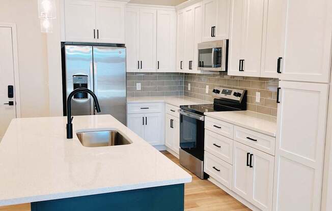 A kitchen with white cabinets and a dark blue island.