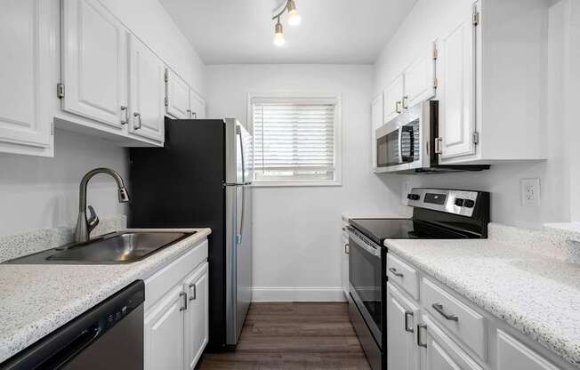 A kitchen with black appliances and white cabinets.