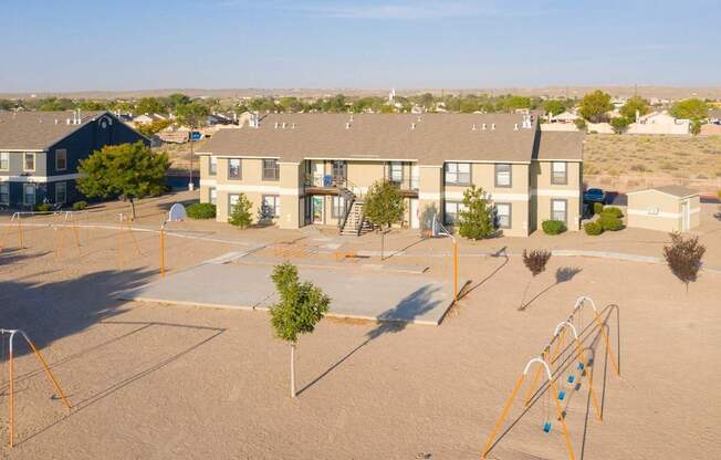 A playground with a slide and swings in front of apartment buildings.