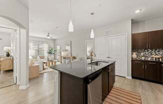 A modern kitchen with a dark countertop and a dining area with a table and chairs.