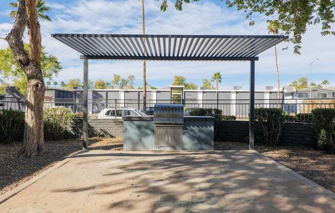 A bus stop with a metal roof and a trash can in front of it.