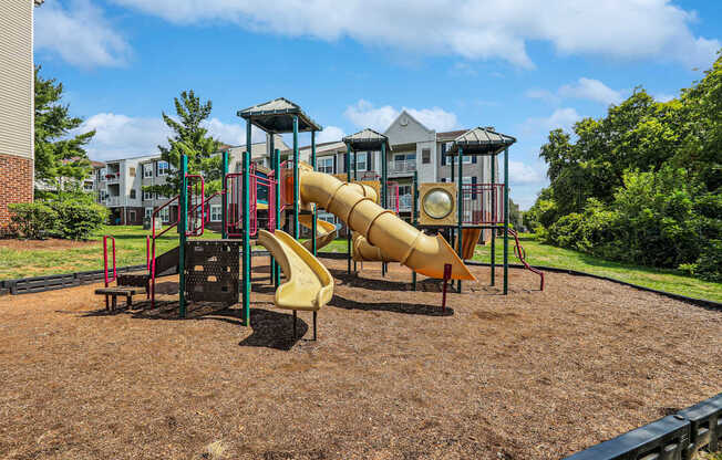A playground with a yellow slide and a red and green structure.