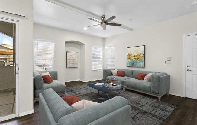 a living room with couches and a ceiling fan