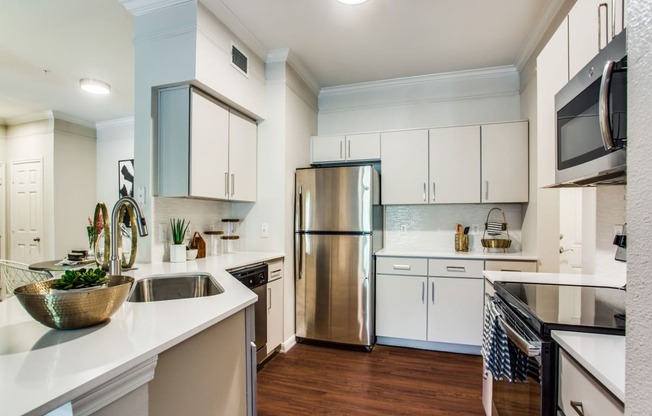 a kitchen with white cabinets and stainless steel appliances at Carrington at Barker Cypress, Cypress, TX