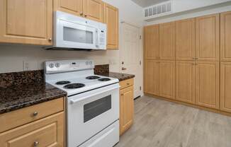 FountainGlen Grand Isle kitchen with a white stove and light wood cabinets.