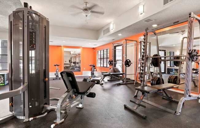 A gym with a variety of equipment including a squat rack, a leg press machine, and a bench press.