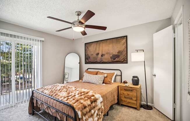 A bedroom with a bed, nightstand, and a painting on the wall.