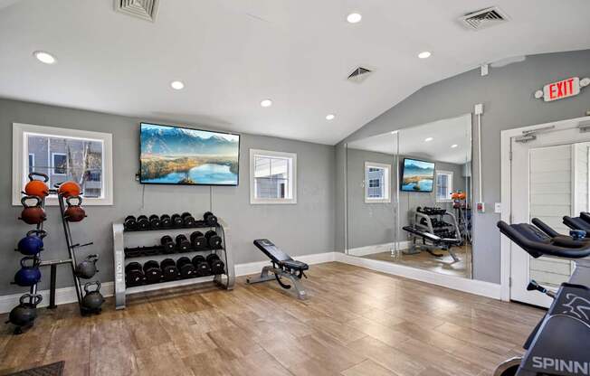 A gym with a Spinn bike and a row of dumbbells.