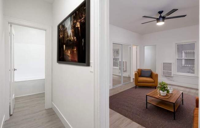 A living room with a brown armchair, a coffee table, and a painting on the wall at Westmore Manor Apartments, California