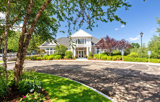 the front of a house with a driveway and trees