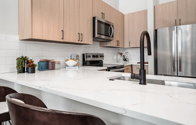 A kitchen with a white countertop and brown chairs.