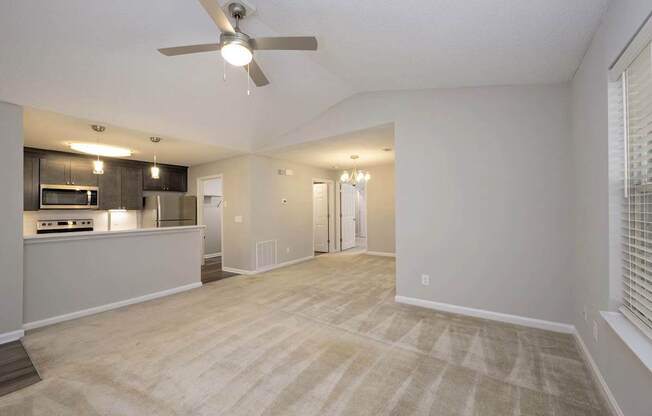 A spacious living room with a ceiling fan and lighting fixtures.