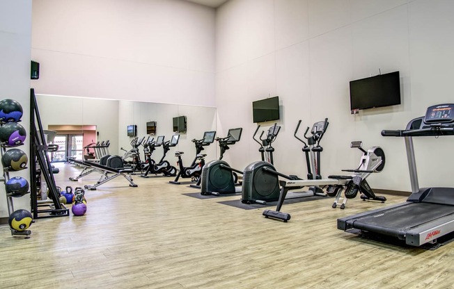 a large fitness room filled with cardio equipment and a tv