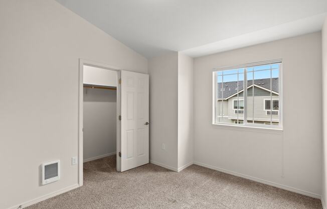 a bedroom with a window and a door to a closet