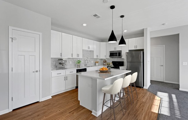 a large white kitchen with an island and white chairs