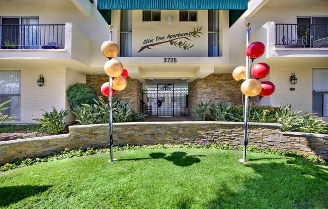 a yard with grass and balloons in front of a building at Olive Tree Apartments, Torrance, CA 90503