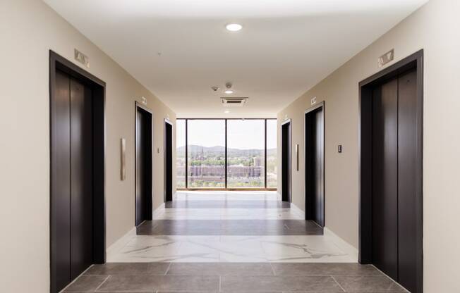 a long corridor with black doors and a view of the mountains