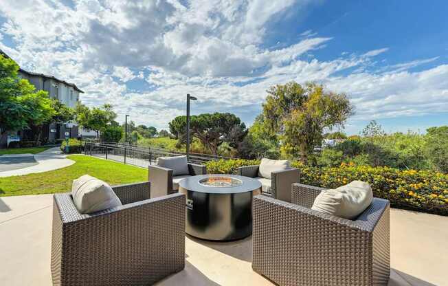 A fire pit and chairs overlooking a green lawn.