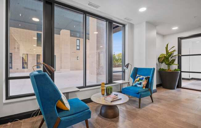 a living room with two blue chairs and a large window