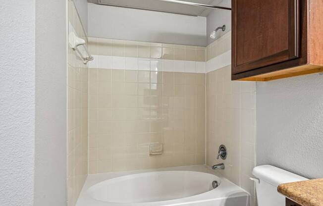 A white bathtub in a bathroom with a brown counter top.