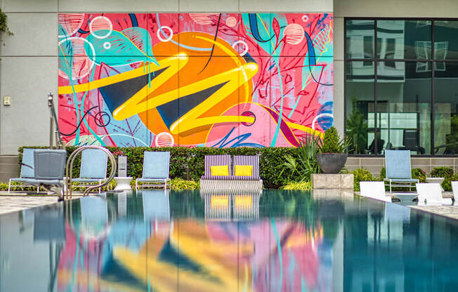A pool with a mural on the wall behind it.
