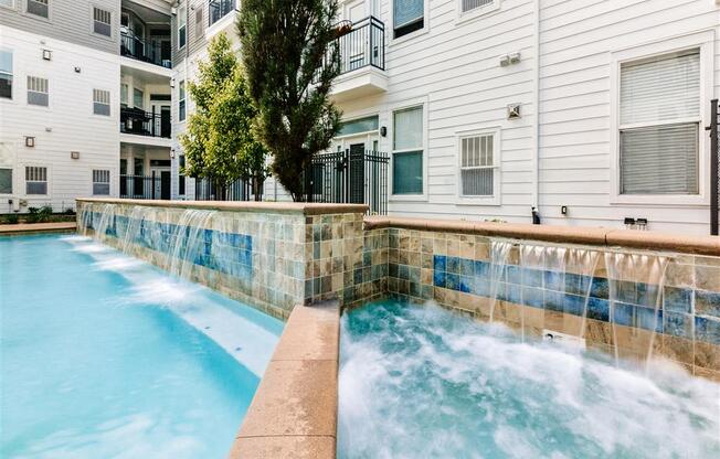 a pool with a waterfall in front of a building