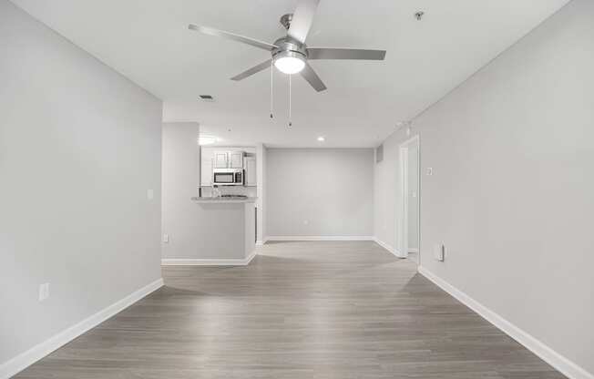 an empty living room with white walls and a ceiling fan