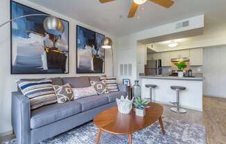 a living room with a couch coffee table and a kitchen in the background