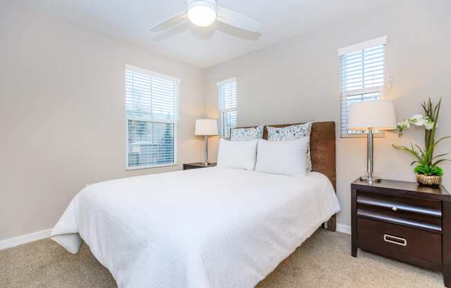 a bedroom with a large white bed and a ceiling fan