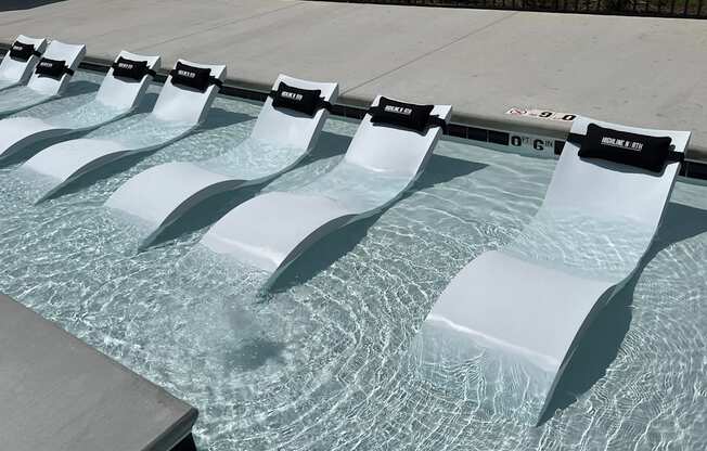 a row of white lounge chairs sit on the edge of a pool